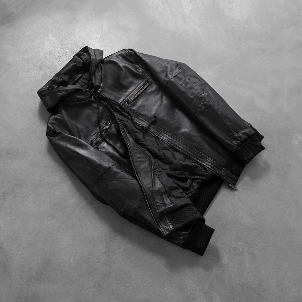 
Passformsperspektiv på  Bouncer Biz Black Leather Hooded Bomber Jacket på modell i naturligt dagsljus