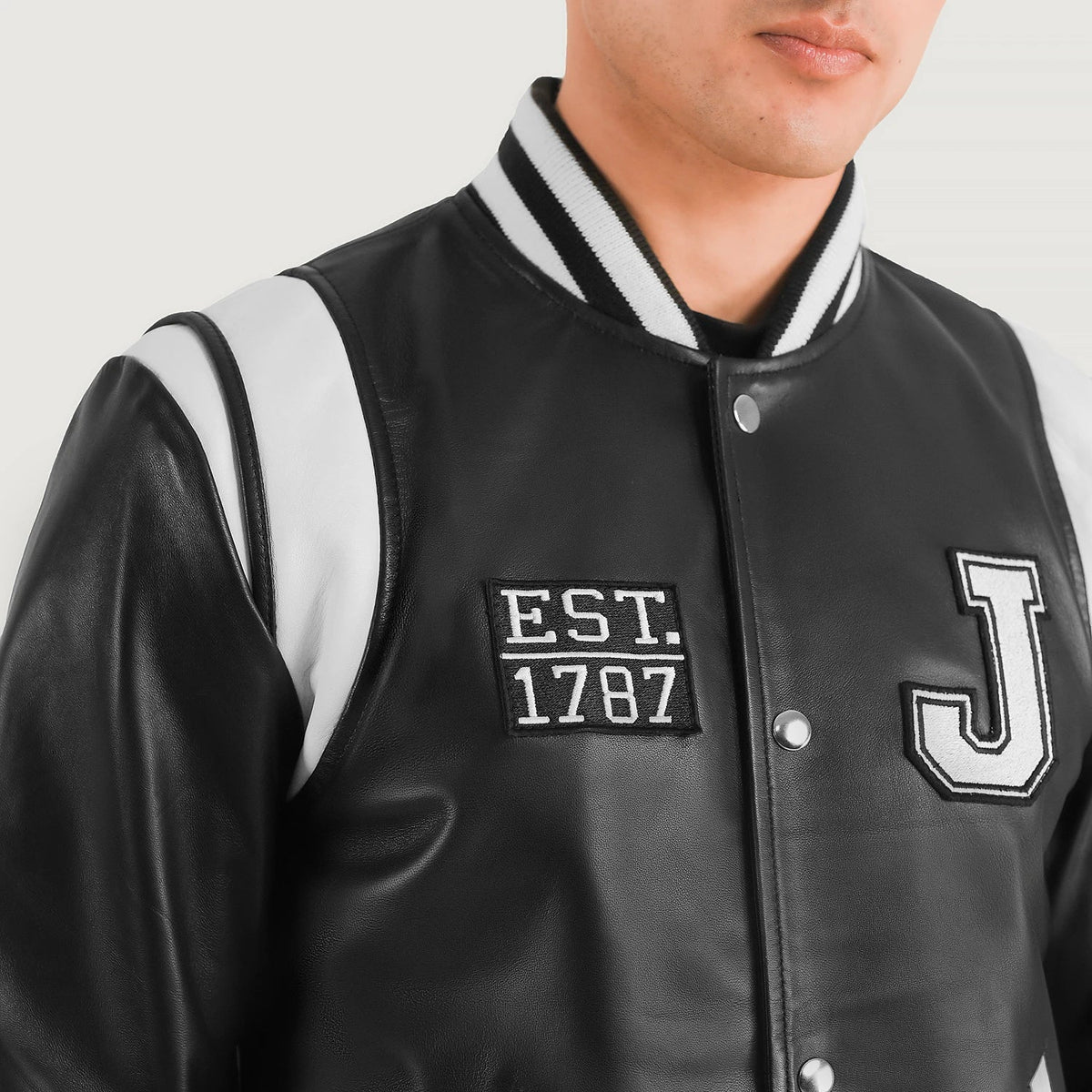 
Närbildsdetalj of Varsity & Snap Button Hardware on Liberte New Jersey Svart Leather Varsity Läderjacka för Herr